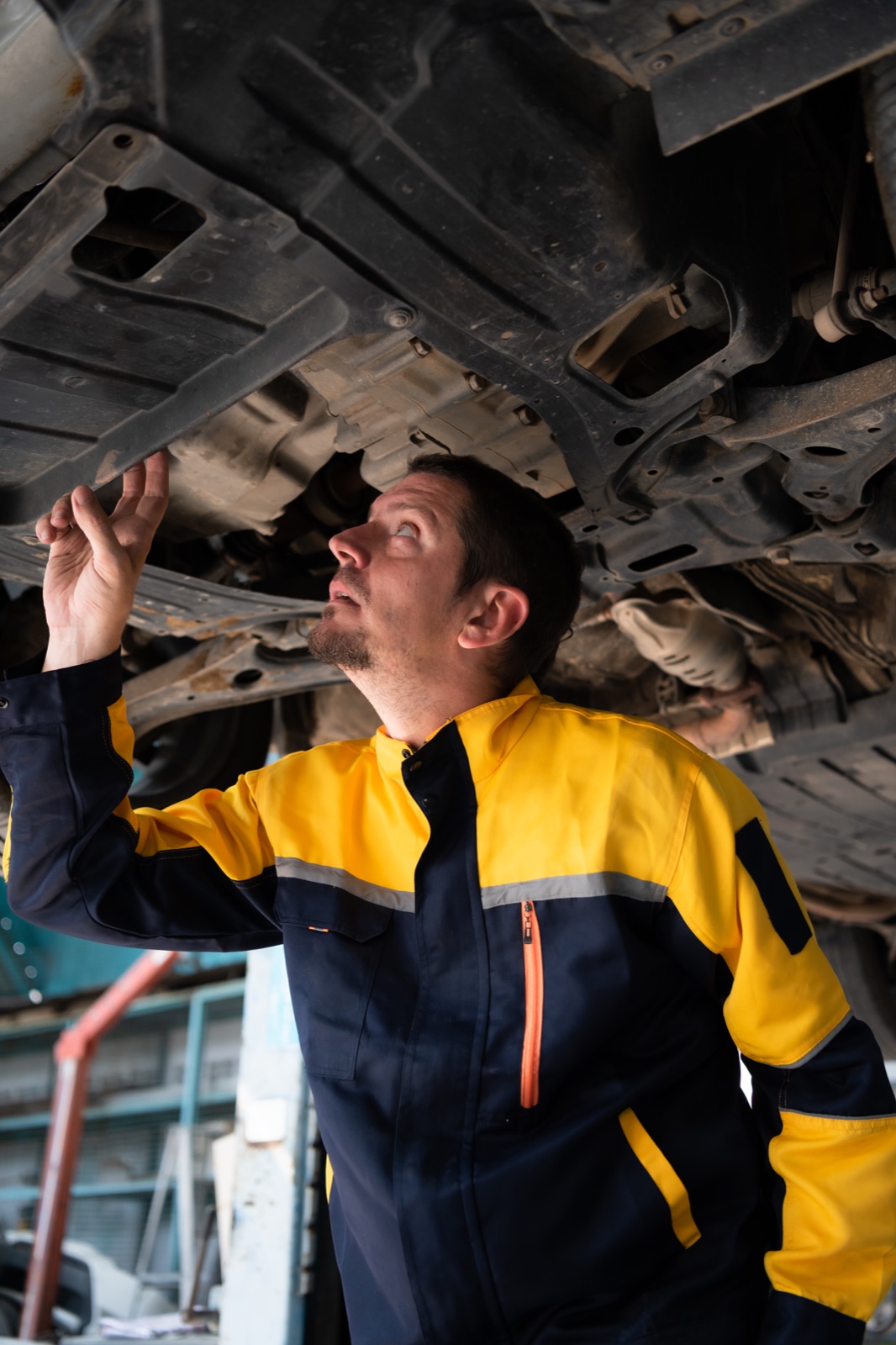 Mechanic in hi-vis working under a vehicle on a hoist in an Australian workshop